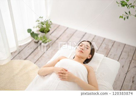 Young woman waiting for massage on bed in beauty salon 120383874