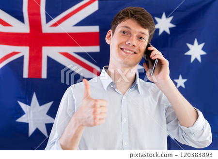 Young guy talking on phone in front of Australian flag Young guy talking on phone in front of Australian flag 120383893