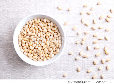 Pine nuts in a white bowl on linen fabric. Also known as pinon, pinoli, or pignoli. Shelled seeds and fruits of Korean pines, Pinus koraiensis. Used for pesto, added to dishes or baked into bread. Pine nuts in a white bowl on linen fabric. Also known as pinon, pinoli, or pignoli. Shelled seeds and fruits of Korean pines, Pinus koraiensis. Used for pesto, added to dishes or baked into bread. 120384429