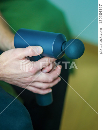 Man Using Percussion Massage Gun for Shoulder Muscle Relief. High quality photo Man Using Percussion Massage Gun for Shoulder Muscle Relief. High quality photo 120384567