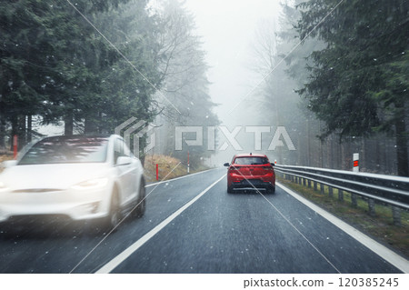 Scenic view nature park highway slippery mountain alpine road driving cars moving fast speed motion. Snowfall danger blizzard bad winter weather conditions. Cold snowy day snowstorm background 120385245