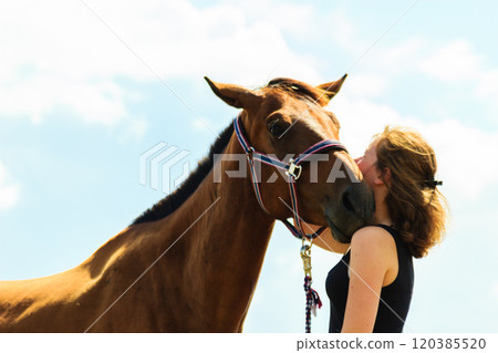 Jockey young girl kissing and hugging brown horse 120385520