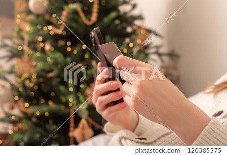 Lodz Poland July 20 2024, hands holding and using mobile phone, iphone smartphone on Christmas 120385575