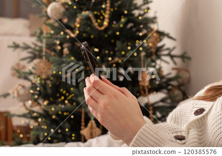 Lodz Poland July 20 2024, hands holding and using mobile phone, iphone smartphone on Christmas 120385576