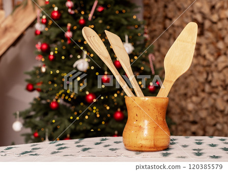 Wooden kitchen utensils on table, Christmas tree on background Wooden kitchen utensils on table, Christmas tree on background 120385579