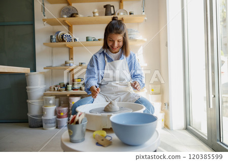 A Creative Woman Engaging in Pottery Crafting Activities within a Vibrant Studio Environment 120385599