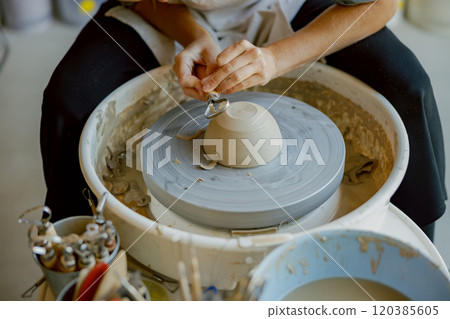 An Artisan Skillfully Crafting a Beautiful Clay Bowl on a Pottery Wheel in their Studio An Artisan Skillfully Crafting a Beautiful Clay Bowl on a Pottery Wheel in their Studio 120385605