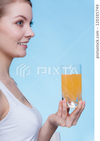 Woman holding glass of orange flavored drink 120385749
