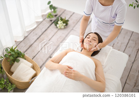 Woman receiving a massage from an esthetician Woman receiving a massage from an esthetician 120386101