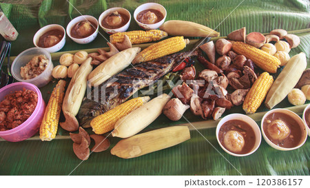 A traditional Filipino sharing meal called boodle fight featuring grilled fish, chicken, lechon, corn, and various vegetables arranged on banana leaves showing the authentic food of the Philippine A traditional Filipino sharing meal called boodle fight featuring grilled fish, chicken, lechon, corn, and various vegetables arranged on banana leaves showing the authentic food of the Philippine 120386157