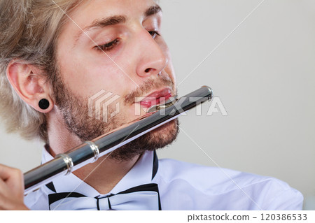Male flutist playing his flute closeup Male flutist playing his flute closeup 120386533