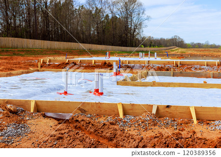 Construction worker prepare foundation of anew building wooden forms pipes are set up on plot of land 120389356