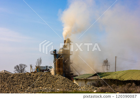 white steam rising up from pipe of small asphalt factory at day time with piles of gravel in a foreground white steam rising up from pipe of small asphalt factory at day time with piles of gravel in a foreground 120390087