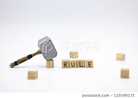 The wooden cubes with the word RULE and the weapon around against white background. The medieval hammer on a wooden cube. 120390135