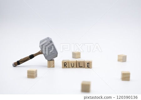 The wooden cubes with the word RULE and the weapon around against white background. The medieval hammer on a wooden cube. 120390136