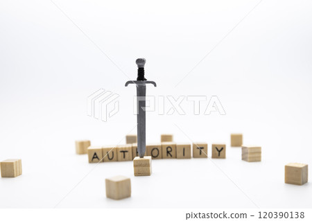 The wooden cubes with the word AUTHORITY and the weapon around against white background. The medieval sword is embedded in a wooden cube. 120390138