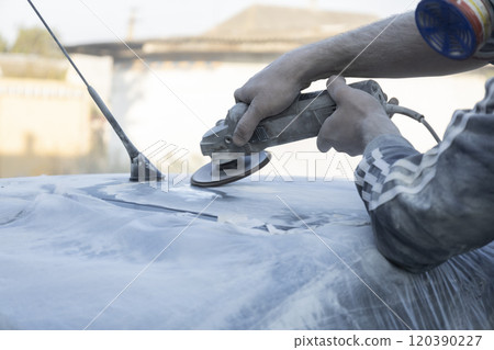 Hands of the auto repairman grinding roof of the car. Hands of the auto repairman grinding roof of the car. 120390227