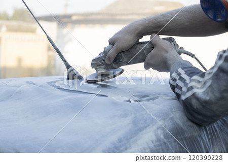 Hands of the auto repairman grinding roof of the car. Hands of the auto repairman grinding roof of the car. 120390228