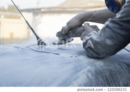 Hands of the auto repairman grinding roof of the car. 120390231