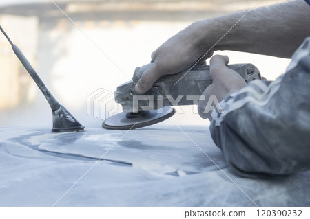 Hands of the auto repairman grinding roof of the car. 120390232