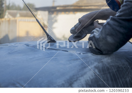 Hands of the auto repairman grinding roof of the car. 120390233