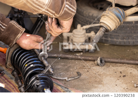 The calloused hands of a mechanic compressing coil spring during DIY car repairs. 120390238