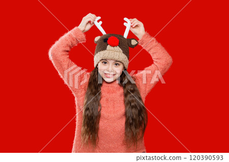 Winter fashion for teenage style. Girl in knitted hat in winter season. Childhood lifestyle. Winter child wardrobe. Teenage girl in Xmas hat isolated on red. Earflap detailing 120390593
