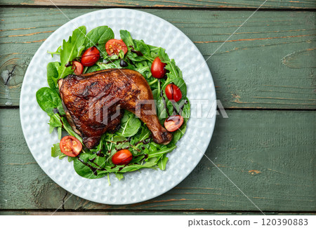 Grilled chicken legs with tomatoes and salad . Top view Grilled chicken legs with tomatoes and salad . Top view 120390883