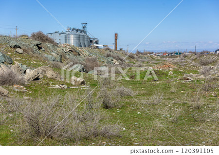 wasteland in an industrial area with grass, piles of rubble and a silo in the background wasteland in an industrial area with grass, piles of rubble and a silo in the background 120391105