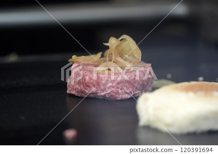 Hamburger being prepared on a moving hot plate 120391694