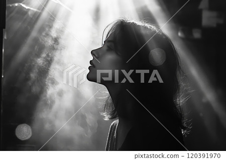 Silhouette of woman in dramatic light beams 120391970