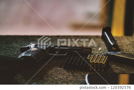 handgun along with a few rounds of ammunition and a magazine. The setting appears to be an indoor environment, possibly a shooting range or an area where firearms are handled and maintained. handgun along with a few rounds of ammunition and a magazine. The setting appears to be an indoor environment, possibly a shooting range or an area where firearms are handled and maintained. 120392576