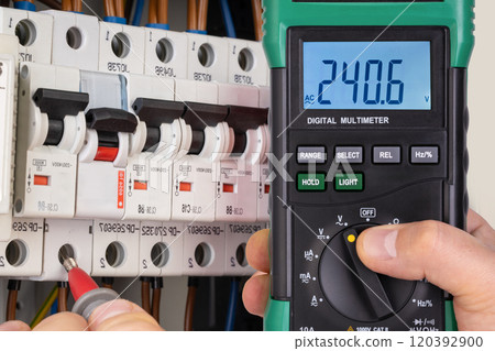Electrician Testing Circuit Breaker with Multimeter 120392900