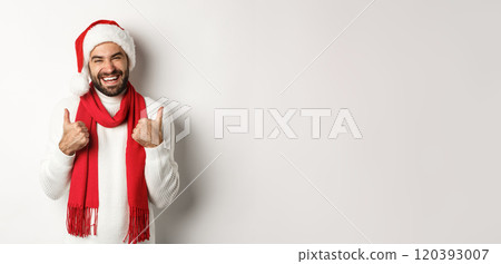 Christmas holidays. Happy man at good new year party showing thumb up, enjoying celebration, wearing santa hat and red scarf, white background Christmas holidays. Happy man at good new year party showing thumb up, enjoying celebration, wearing santa hat and red scarf, white background 120393007