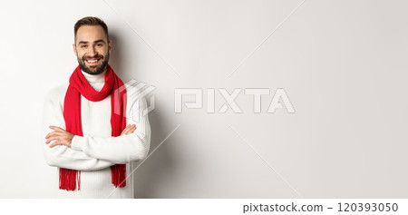 Christmas holidays and celebration concept. Handsome bearded man in sweater celebrating new year, wearing red scarf and smiling, standing over white background 120393050