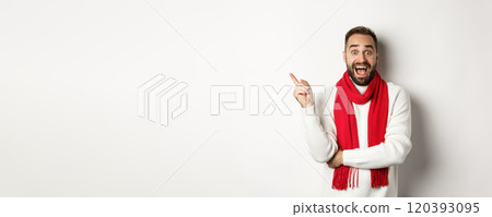 Christmas shopping and winter holidays concept. Surprised man pointing finger left, showing promo offer, standing over white background 120393095