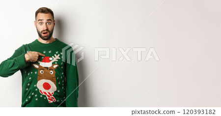 Winter holidays and christmas. Confused bearded guy pointing at himself, being startled with offer, standing over white background in sweater 120393182
