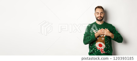 New year celebration and winter holidays concept. Young relaxed man feeling nostalgic, holding hands on heart and close eyes, dreaming about something on Christmas New year celebration and winter holidays concept. Young relaxed man feeling nostalgic, holding hands on heart and close eyes, dreaming about something on Christmas 120393185