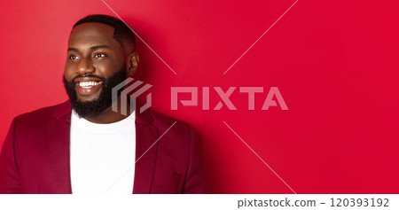 Close-up of handsome african american man with beard, looking left and smiling joyful, standing over red background 120393192