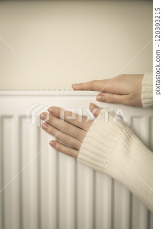 Individual home heating system. Female hands on a warm radiator. 120393215