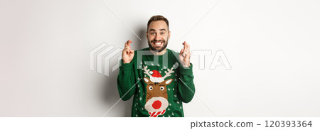 Christmas, holidays and celebration. Hopeful happy guy making wish, keep fingers crossed for good luck and smiling, standing over white background 120393364
