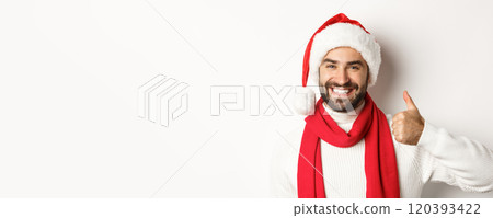 New Year party and winter holidays concept. Close-up of happy man in Santa hat showing thumbs up in approval, like and agree, standing over white background New Year party and winter holidays concept. Close-up of happy man in Santa hat showing thumbs up in approval, like and agree, standing over white background 120393422