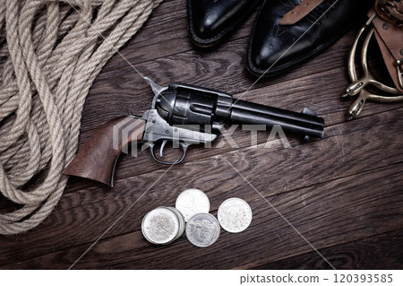 Old western revolver gun with silver dollars and cowboy boots Old western revolver gun with silver dollars and cowboy boots 120393585