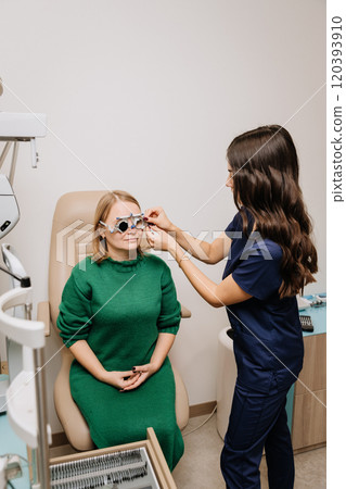 Optometrist fitting trial lenses on eye exam for vision testing and prescription adjustment 120393910
