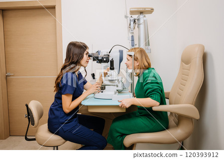 Professional eye exam with optometrist using advanced slit lamp equipment in a modern clinic Professional eye exam with optometrist using advanced slit lamp equipment in a modern clinic 120393912