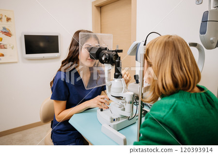 Optometrist performing an eye exam with slit lamp equipment in a modern medical clinic 120393914