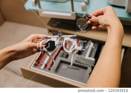 Hands adjusting trial lenses for precise eye tests in a modern optometry clinic Hands adjusting trial lenses for precise eye tests in a modern optometry clinic 120393918