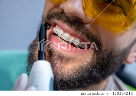 Man in protective glasses in dentist chair having teeth care procedures Man in protective glasses in dentist chair having teeth care procedures 120394216