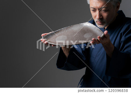 Image of a male potter holding a plate 120396838