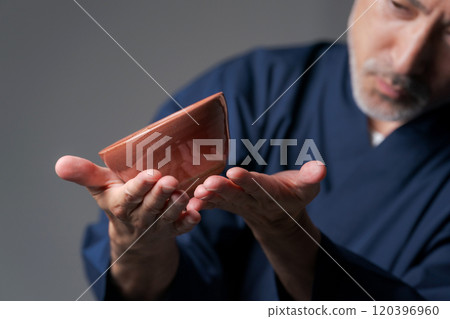 Image of a male potter holding a tea bowl 120396960